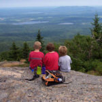 Three Children Sitting on a Rock Overlooking a Valley